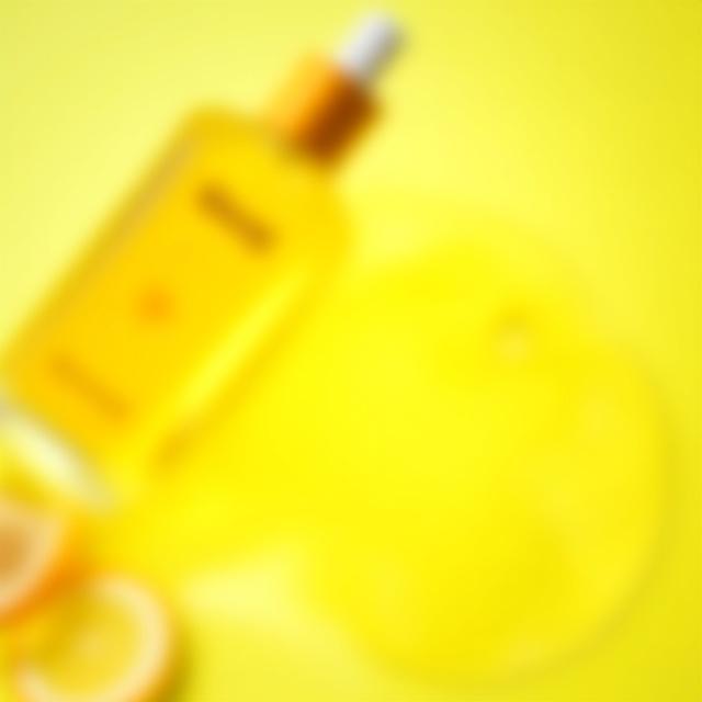 Flacone di olio corpo illuminante con gocce d'olio visibili.